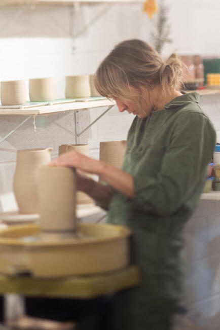 Sarah Veak of Veak Ceramics trimming a clay pot in her studio